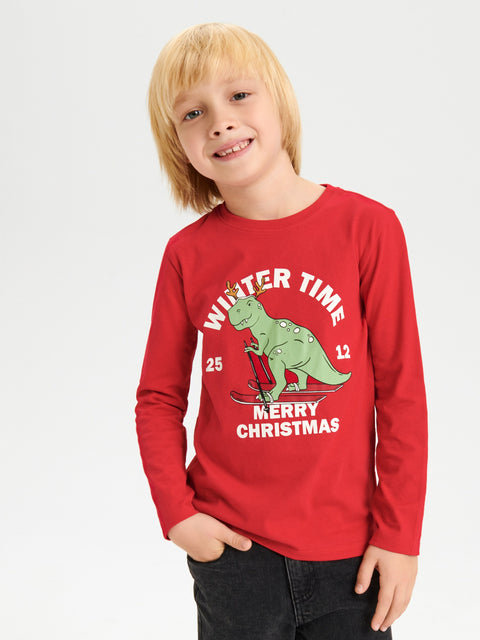 Child wearing a red long-sleeve shirt with a Christmas dinosaur design on a white background