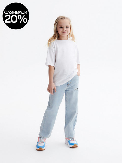 Young girl wearing a white t-shirt and light blue jeans on a white background with a cashback 20% badge.
