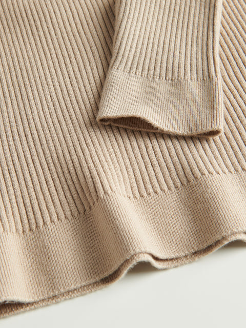 Close-up of a beige ribbed knit sweater on a light background