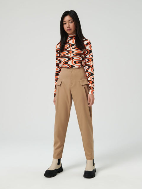 Person wearing a patterned top and beige pants on a white background
