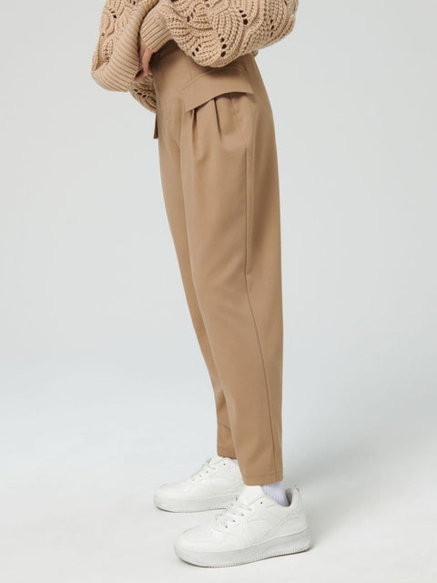 Person wearing beige pants and a knitted sweater on a white background