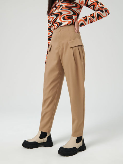 Person wearing beige pants and a colorful top on a white background