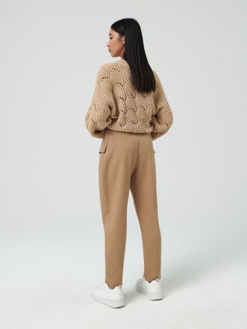 Woman wearing a beige knitted sweater and pants on a white background