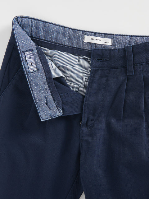 Navy pants with a close-up of the waistband and lining on a light gray background