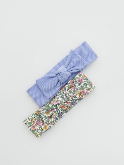 Two headbands, one purple with a bow and one floral patterned, on a light gray background.