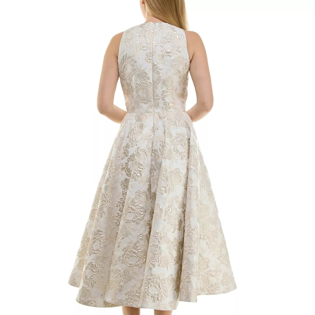 A woman shown from the back wearing a sleeveless, knee-length cream and beige floral lace dress with a fitted waist and flared skirt, paired with metallic gold high-heeled sandals, against a plain white background.