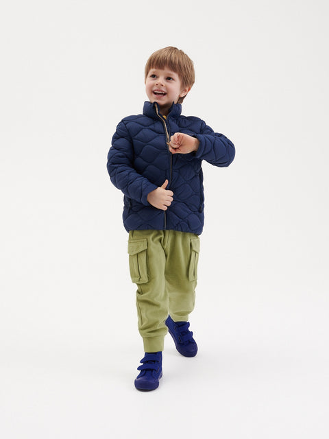 Child wearing a navy puffer jacket and green cargo pants on a white background
