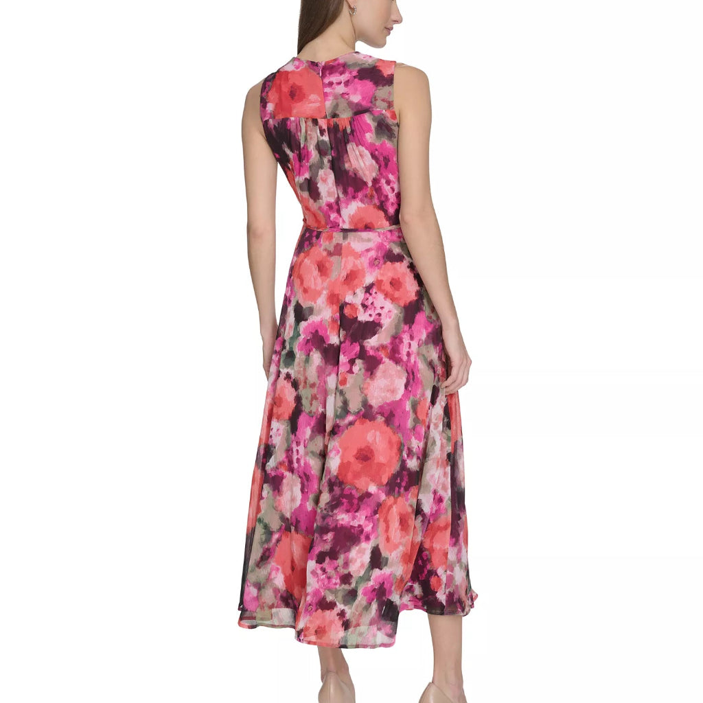 A woman shown from the back wearing a sleeveless midi dress with a vibrant pink, red, and purple floral watercolor print, paired with beige high heels against a plain white background.