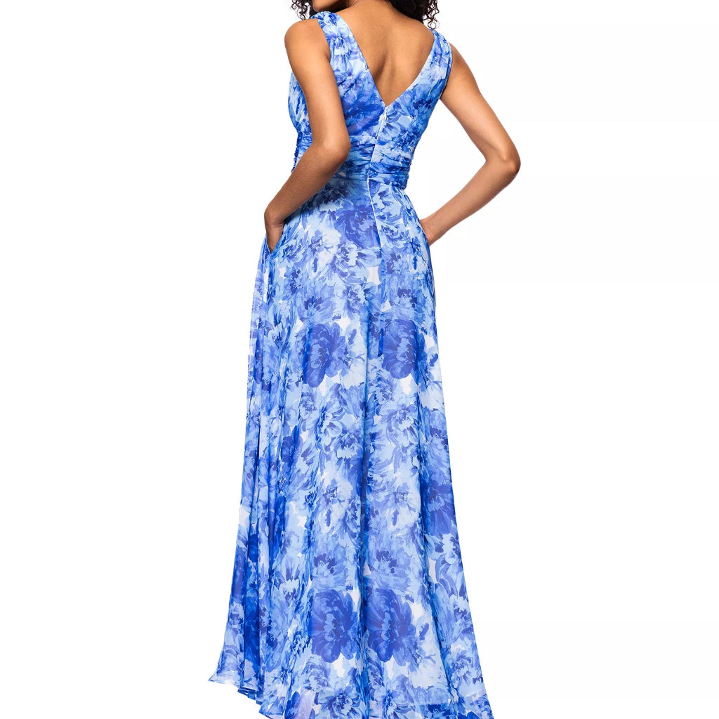 A woman modeling a sleeveless, floor-length blue floral maxi dress with a V-neckline and back pockets, shown from a three-quarters back view against a plain white background.