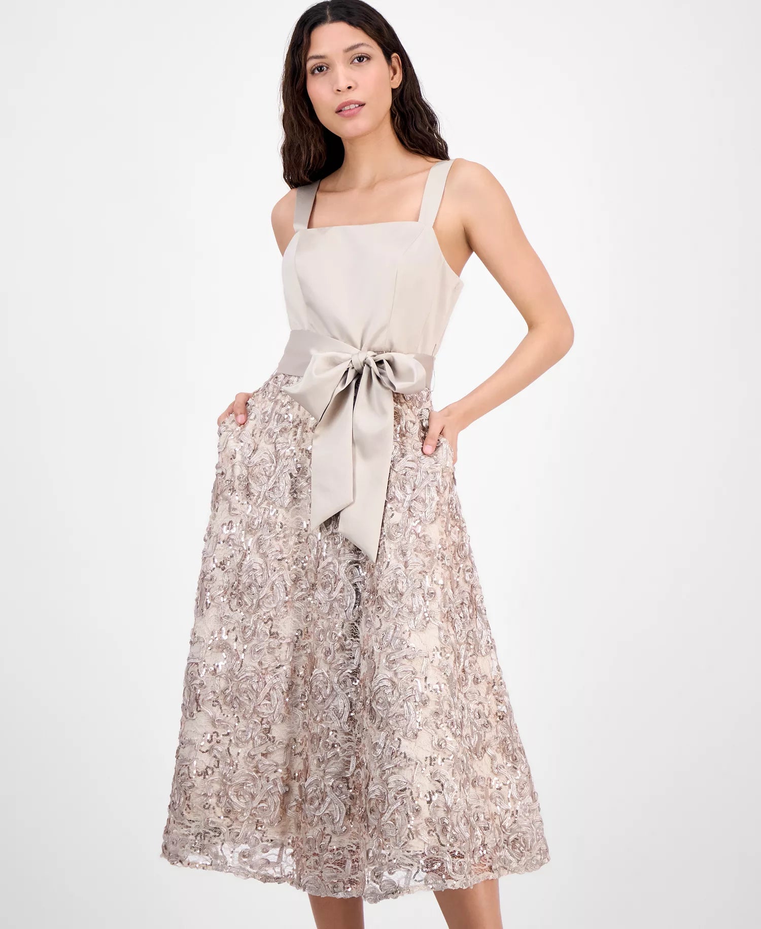 Woman wearing a beige sleeveless top and floral skirt with a white background