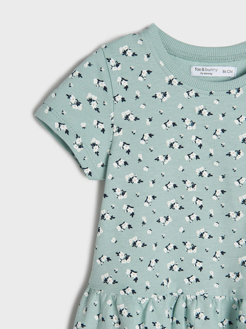 Green dress with black and white floral pattern on a light gray background