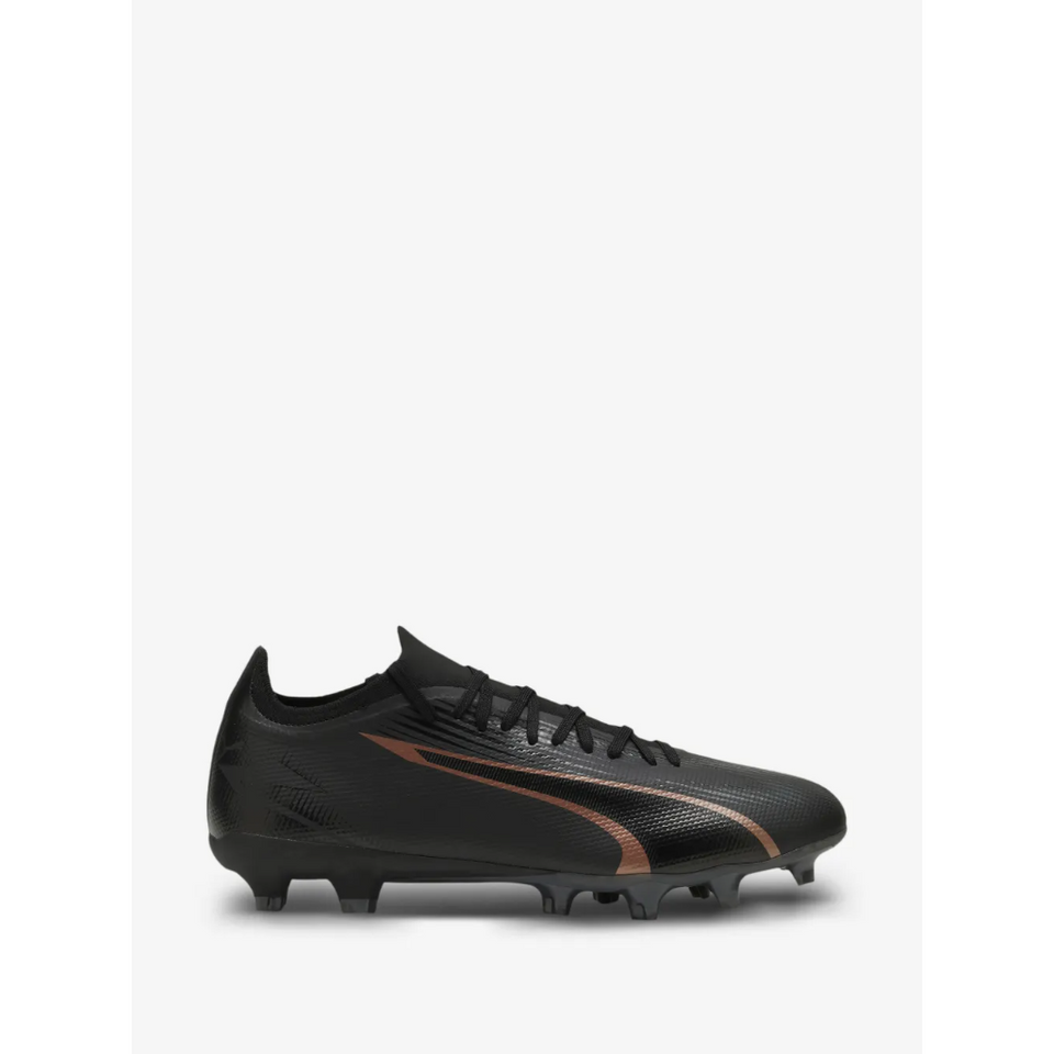 A black Puma soccer cleat with a metallic bronze Puma Formstrip on a light gray background.