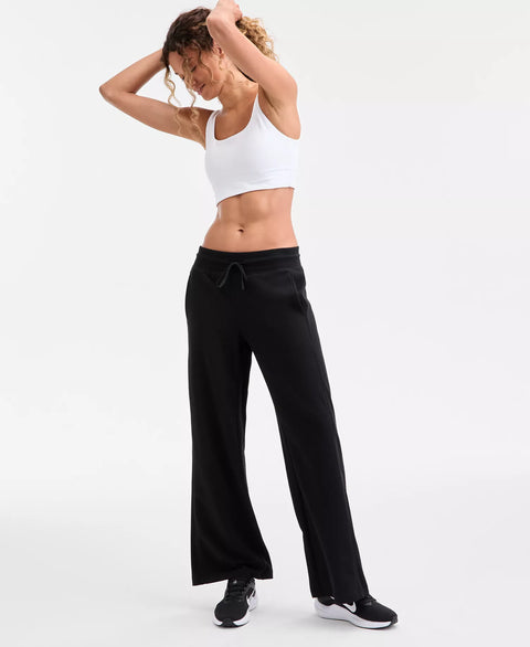 Woman wearing a white sports bra and black pants on a white background