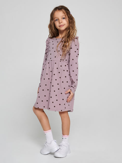 Young girl wearing a polka dot dress on a plain background