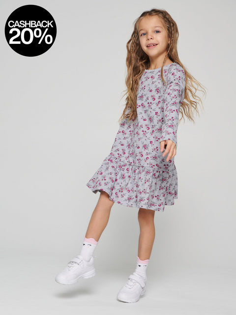 Young girl wearing a floral dress on a plain background