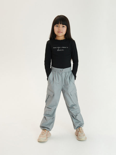 Child wearing a black shirt and light gray pants on a white background