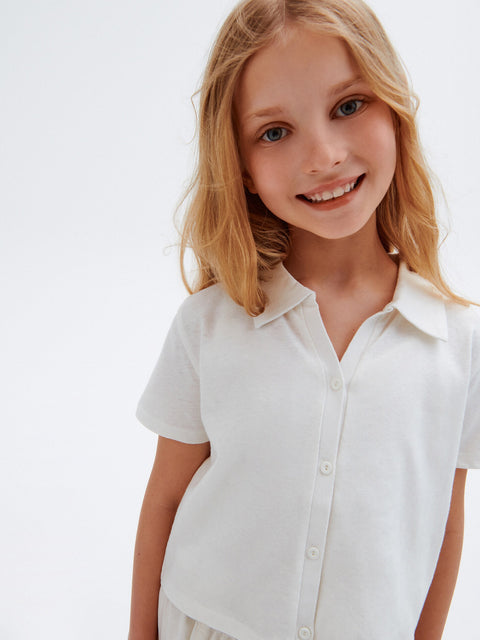 Young girl wearing a white shirt against a plain background
