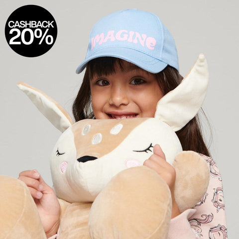 Child holding a plush toy with a 'Imagine' cap on a gray background