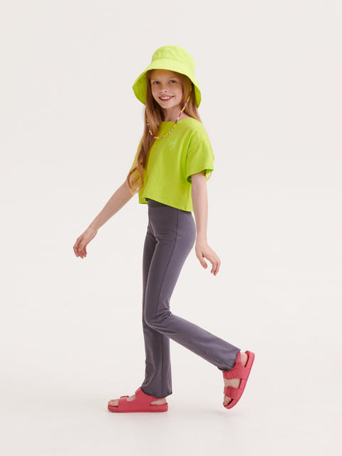 Child wearing a bright green shirt, gray pants, and a yellow hat on a white background
