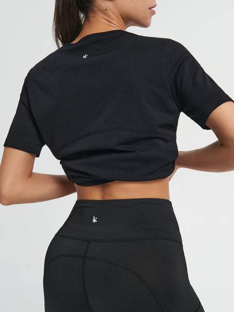 Person wearing a black athletic outfit with a logo on a plain background