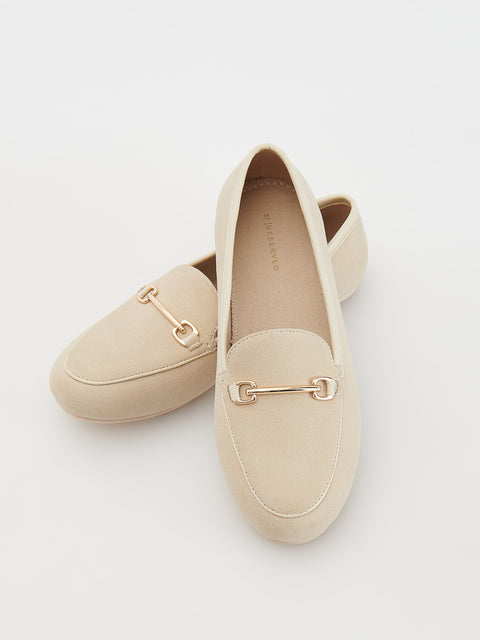 Pair of beige loafers with gold accents on a light gray background