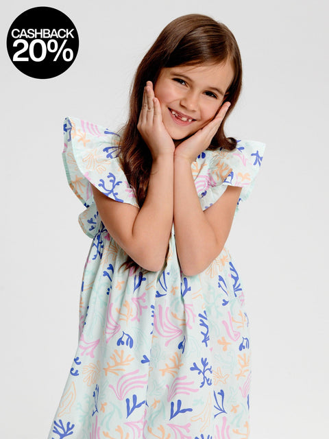 Young girl wearing a colorful dress with a floral pattern on a plain background