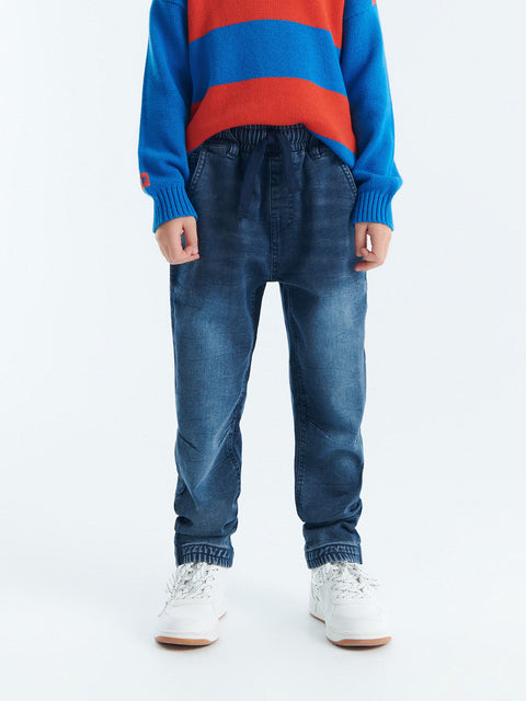 Person wearing a blue and red striped sweater with blue jeans on a white background