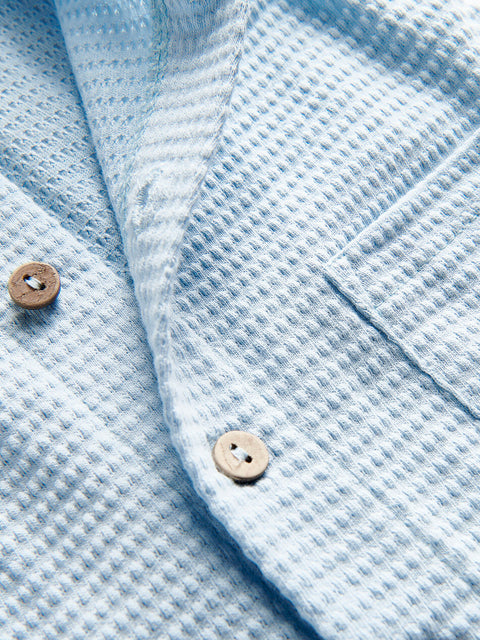 Close-up of a light blue textured fabric with buttons