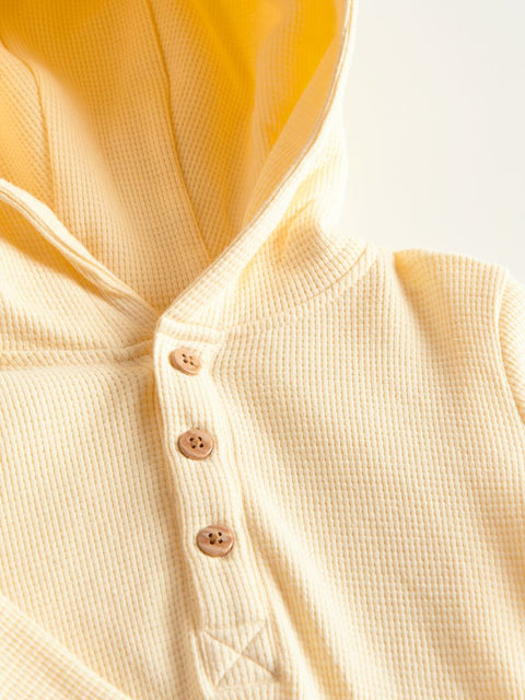 Close-up of a beige textured shirt with buttons on a light background