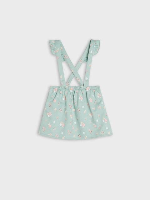 Green dress with floral pattern and suspenders on a light gray background