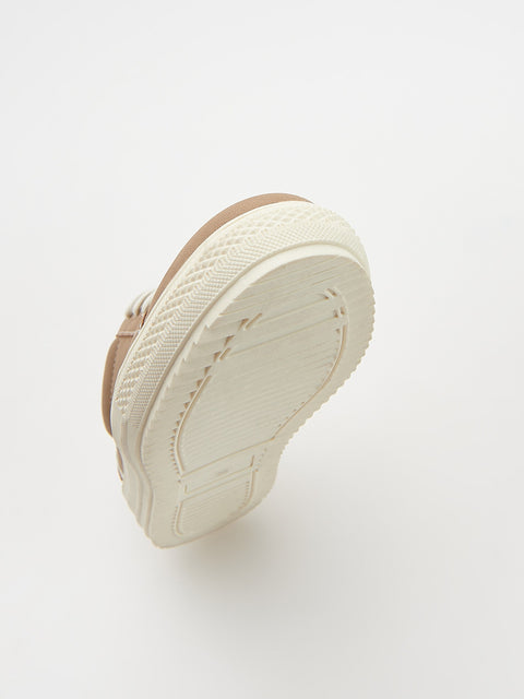 White sneaker with brown sole on a white background
