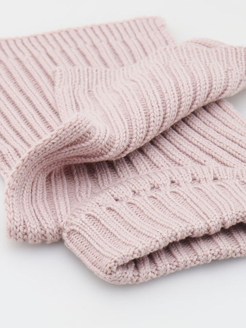 Folded pink knitted blanket on a light gray background