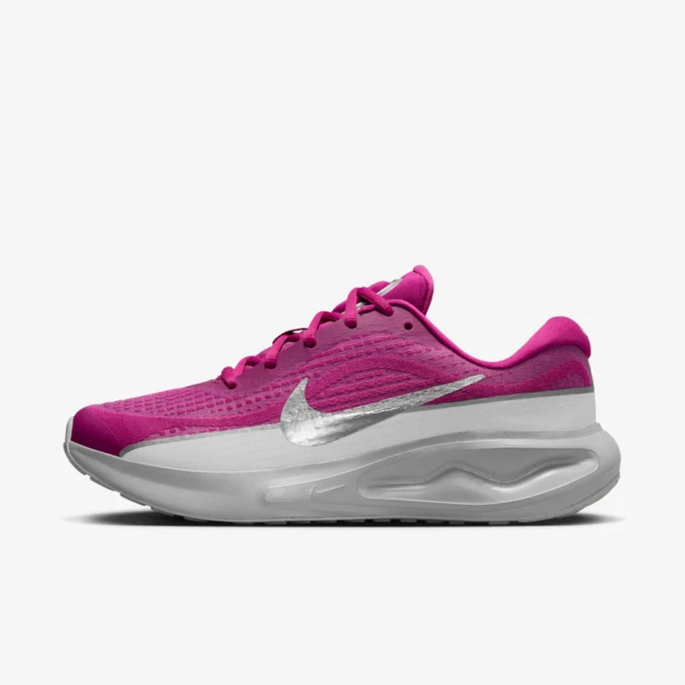 A Nike running shoe in vibrant magenta pink with a metallic silver Swoosh and a thick white cushioned sole, shown from a side profile on a light gray background.