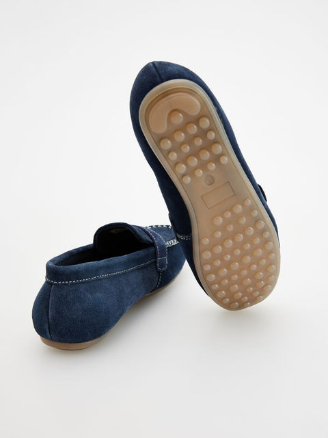 Pair of blue loafers with beige soles on a white background