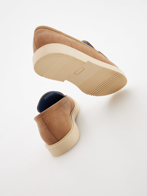 Tan slip-on shoes with a white sole on a light gray background