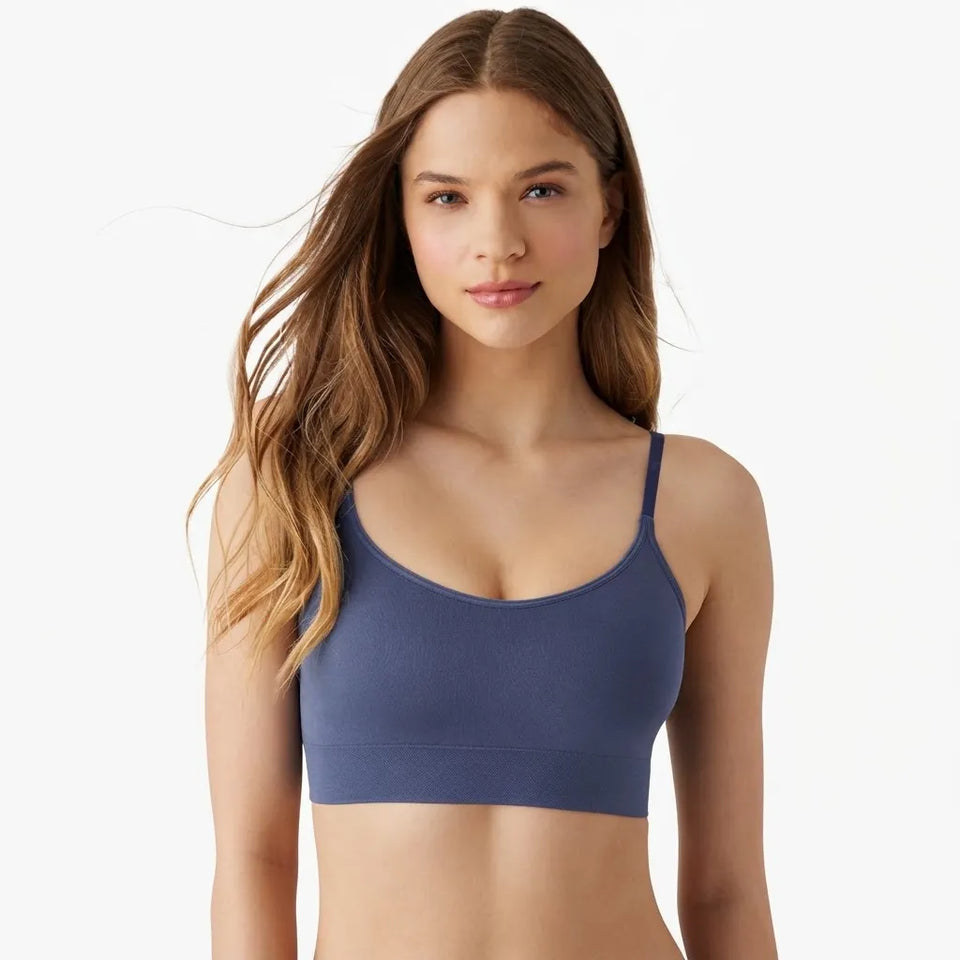 A woman modeling a solid slate blue sports bra against a clean white background.