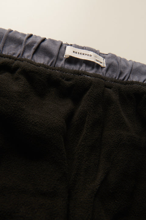 Black garment with a 'RESERVED' tag on a neutral background