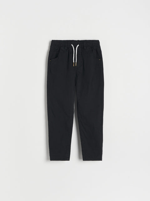 Black pants with a white drawstring on a light gray background