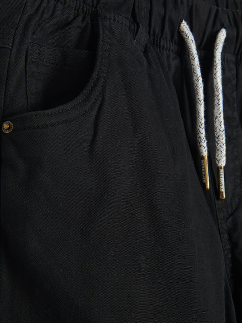 Black pants with a drawstring detail on a dark background