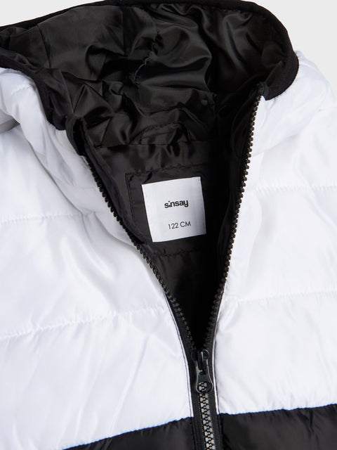 Close-up of a white puffer jacket with black hood and zipper, featuring a 'Sinsay' label.