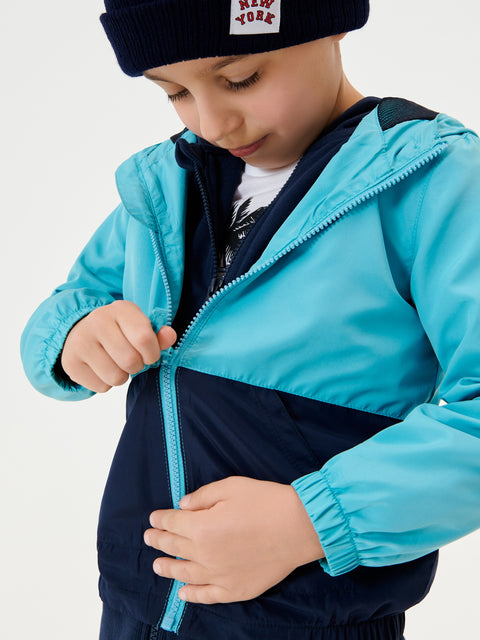 Child wearing a blue and navy jacket with a white background