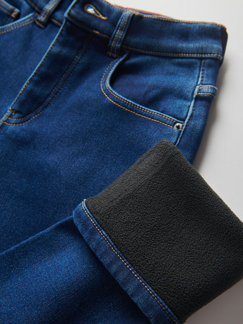 Close-up of blue jeans with a black patch on a light gray background