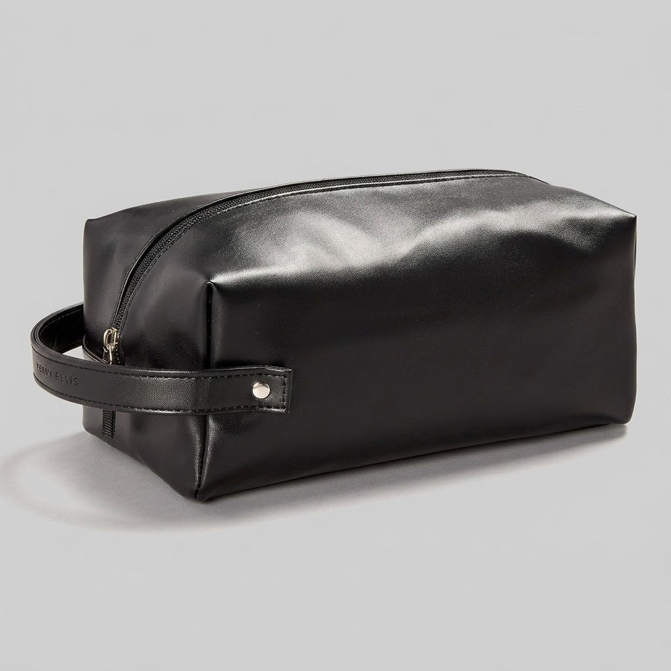 A black leather zippered toiletry bag with a side handle, shown on a neutral light gray background.