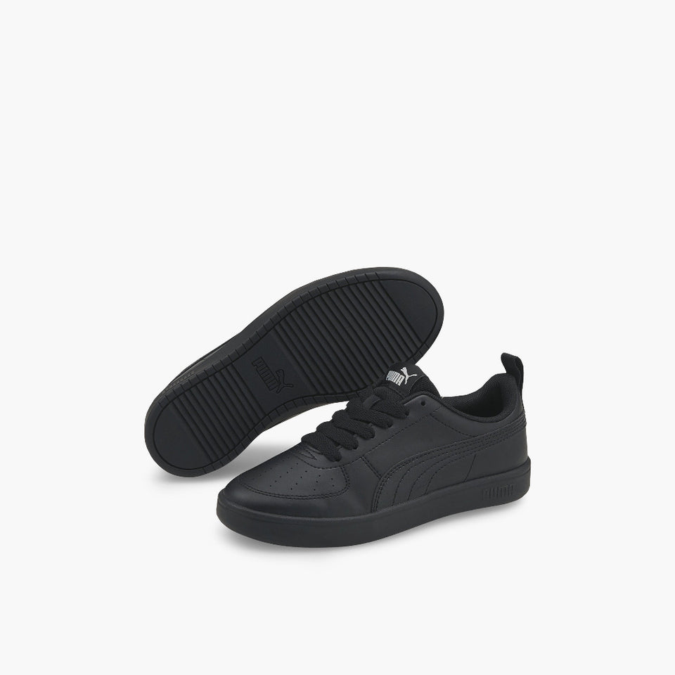 A pair of black Puma sneakers shown on a clean white background, with one shoe standing upright to display the side profile and the other lying on its side to show the textured black sole.