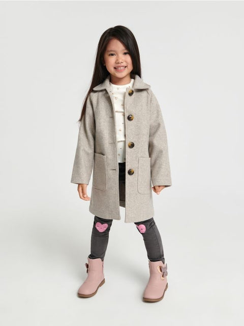 Young girl wearing a gray coat with a white background