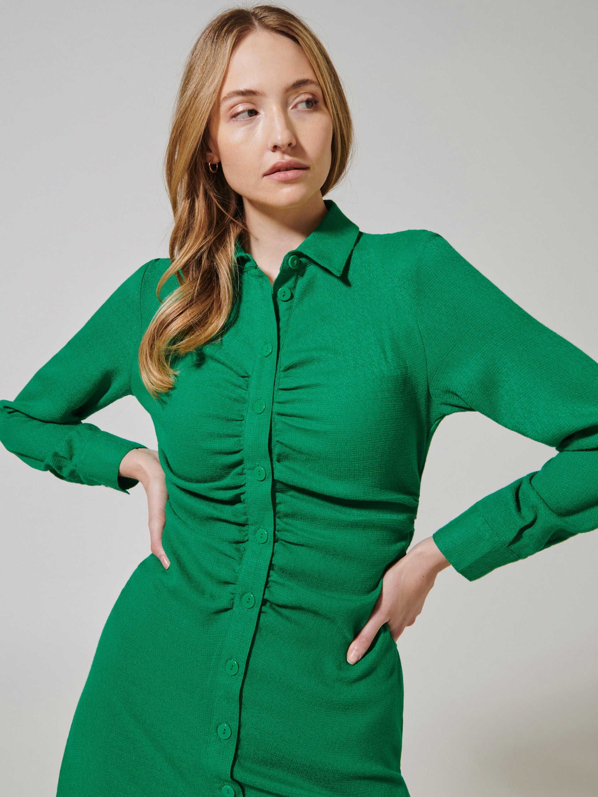 Woman wearing a green dress against a plain background
