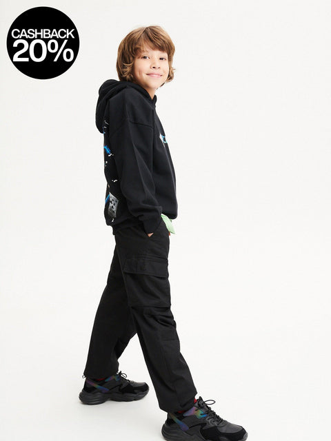 Child wearing a black hoodie and pants on a white background