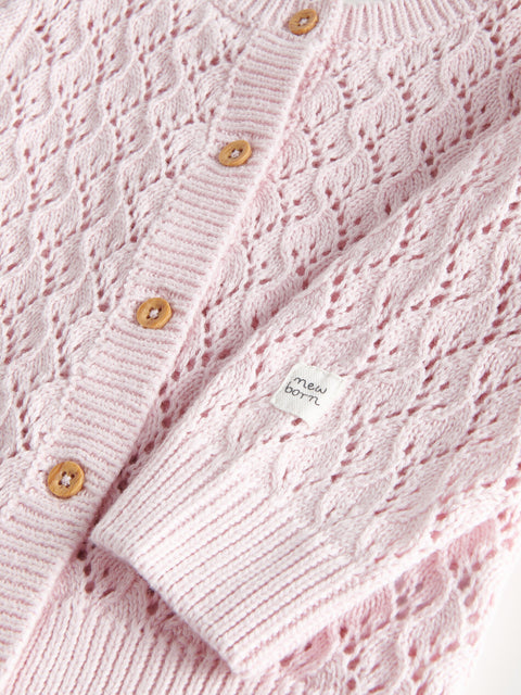 Close-up of a pink knitted cardigan with button details and a brand label.