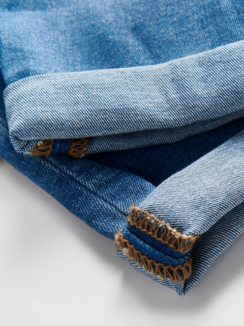 Close-up of blue denim fabric with brown stitching on a white background