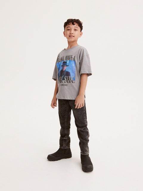 Child wearing a graphic t-shirt and jeans on a white background